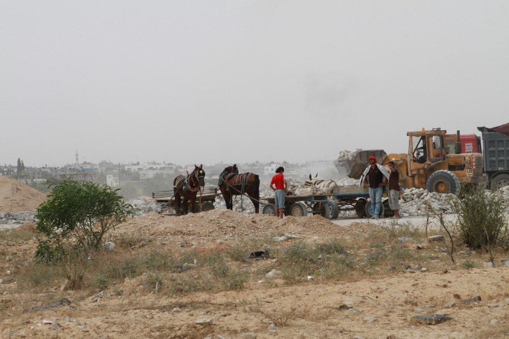 Local Palestinians harvest building materials from the rubble of bombed buildings.